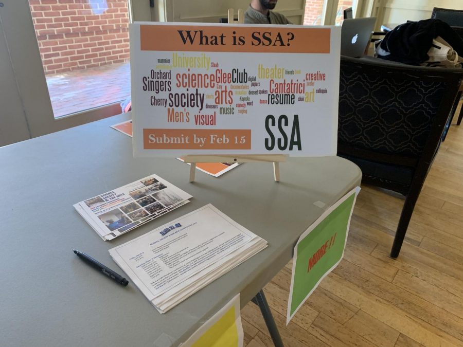 A poster at a table in the Commons Living Room explains the different aspects of Science, Society and the Arts Conference. Photo by Coleman Martinson, 21.
