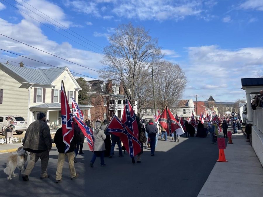 A parade of people carrying Confederate flags down a street.