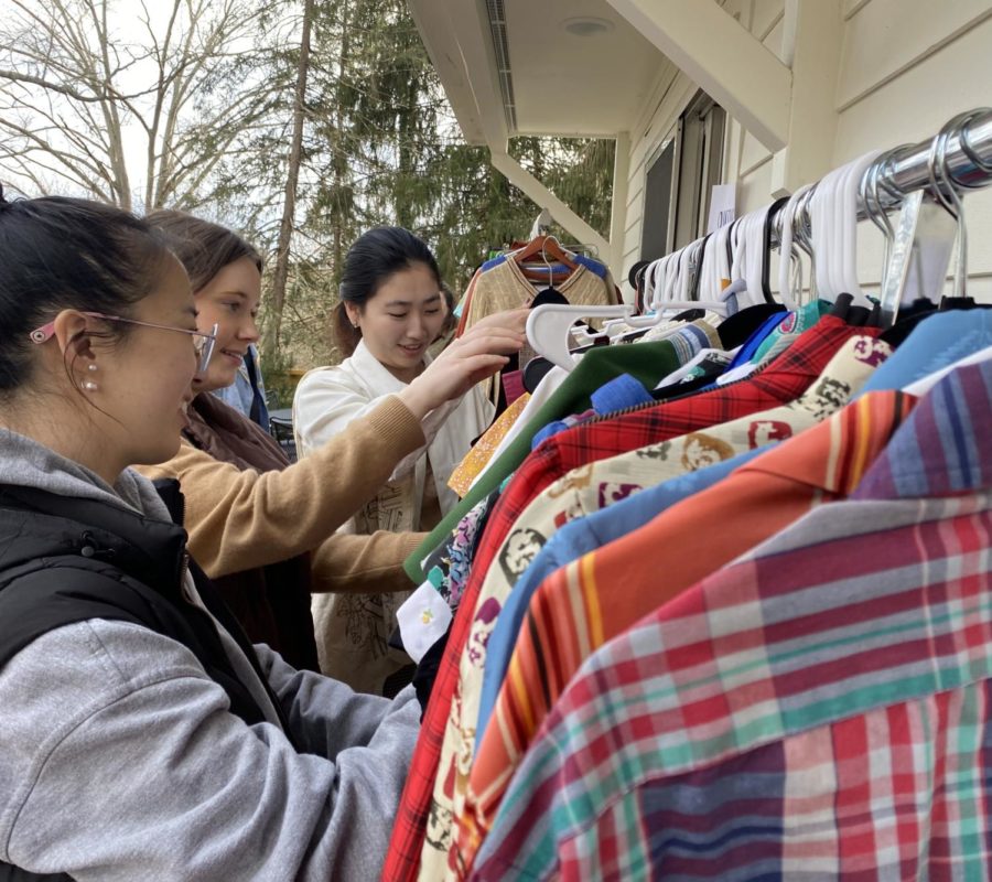 Three people touch and look through a rack of colorful clothing.