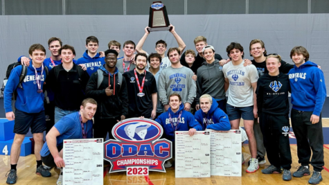 A group of men pose, smiling, behind an ODAC logo sign. One man holds a trophy over his head.
