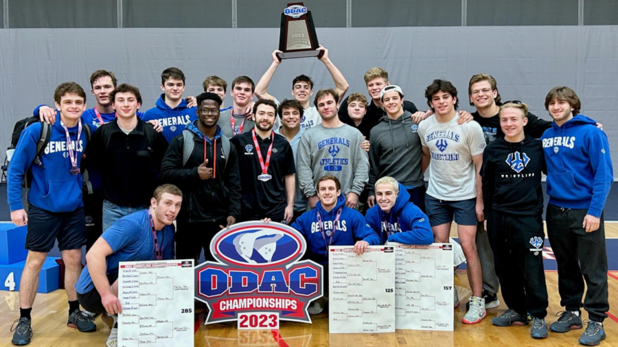 A+group+of+men+pose%2C+smiling%2C+behind+an+ODAC+logo+sign.+One+man+holds+a+trophy+over+his+head.