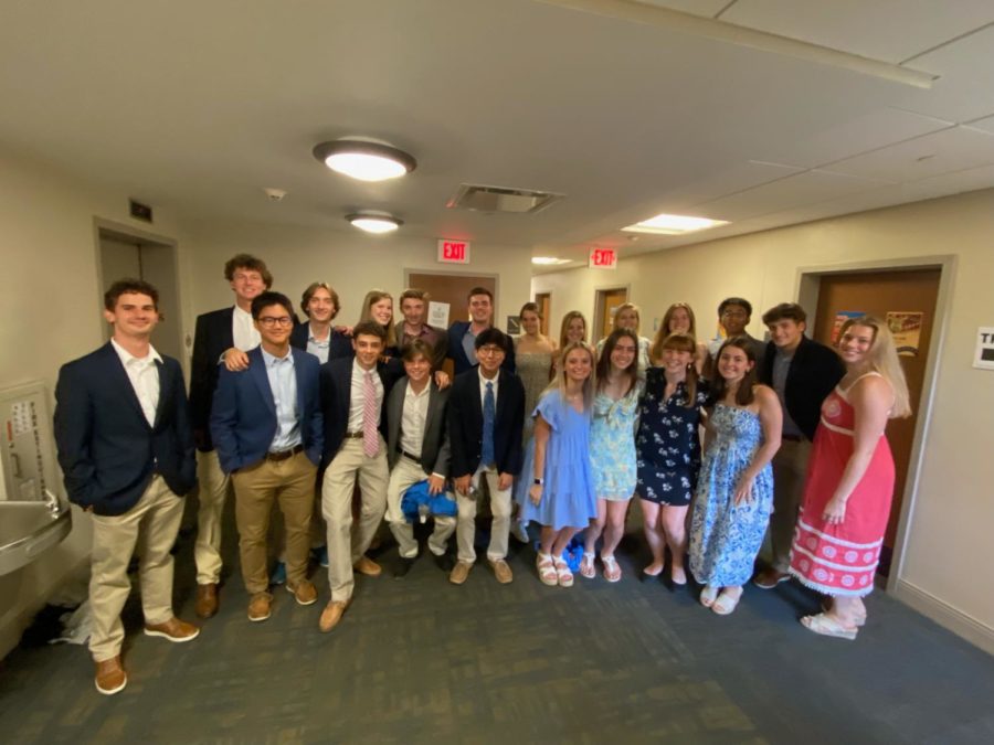 A group of people dressed formally stand together in a dorm hallway.