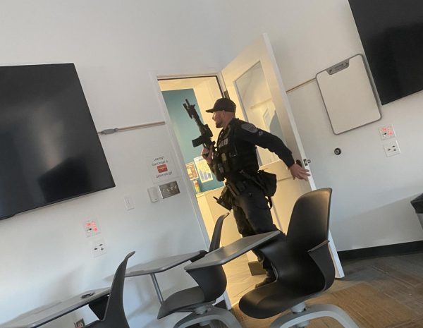 A law enforcement officer carrying a rifle leaves a room in the Center for Global Learning, amid an hours-long campus search yesterday.