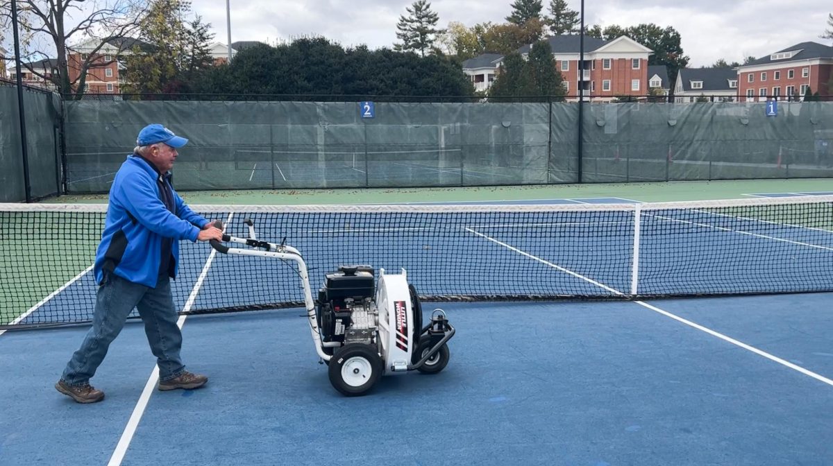 Timmy Hill blows leaves off of the outdoor tennis courts.
