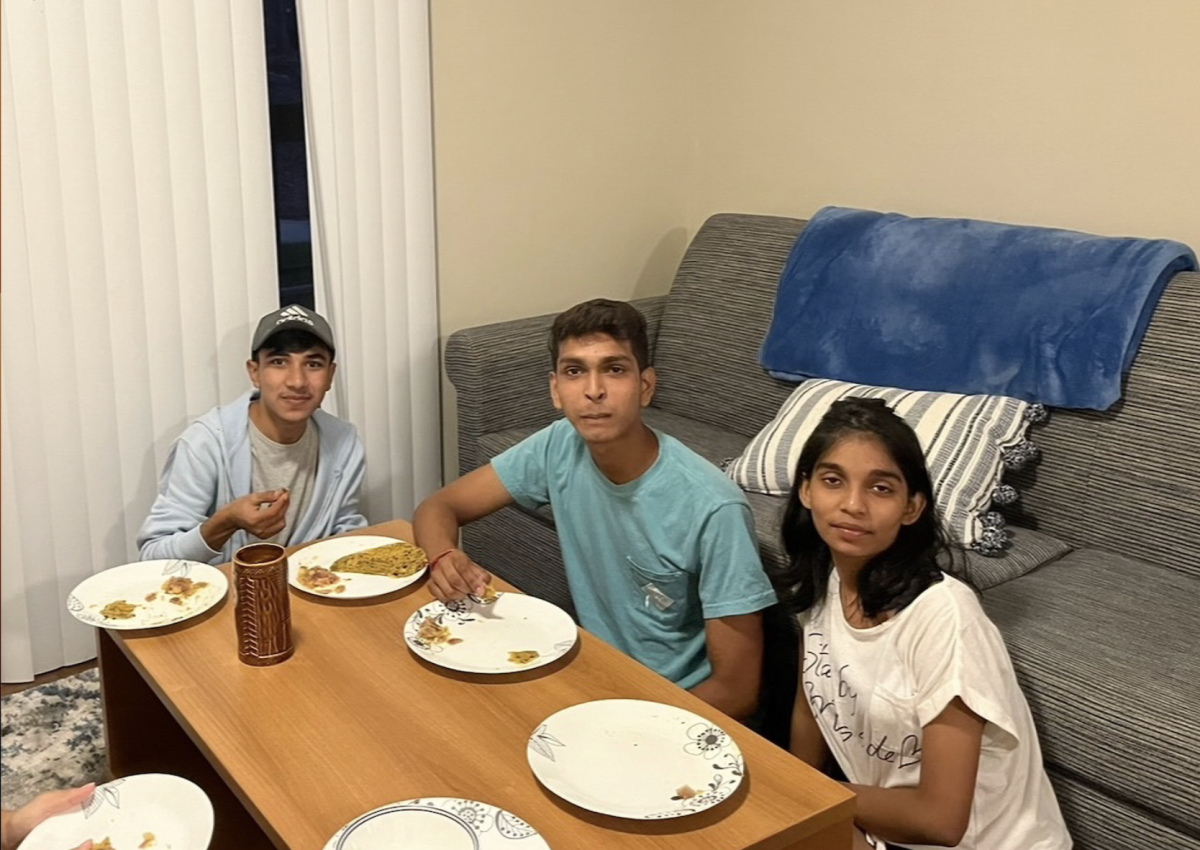 International students Anshika Patel, Hamza Zia and Vishal Pal eating traditional southeast Asian food in the apartment where Patel broke her finger last year.